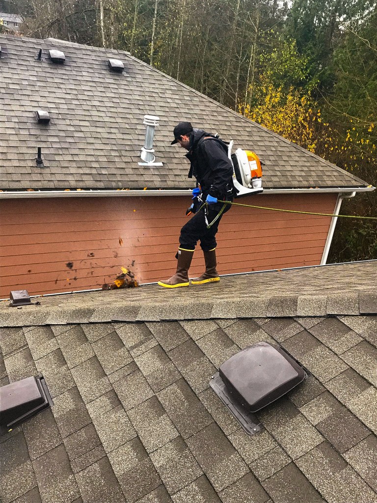 man cleaning gutters with blower